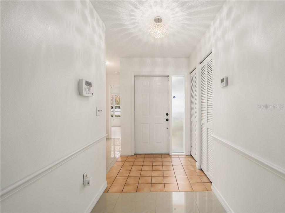 An entryway features white walls, a tiled floor, a white front door, and a light fixture — 2437 SW 20TH COURT, OCALA, FL