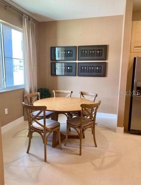 A dining area features a round wooden table with four chairs and four framed prints — 7657 RECIFE DRIVE, KISSIMMEE, FL