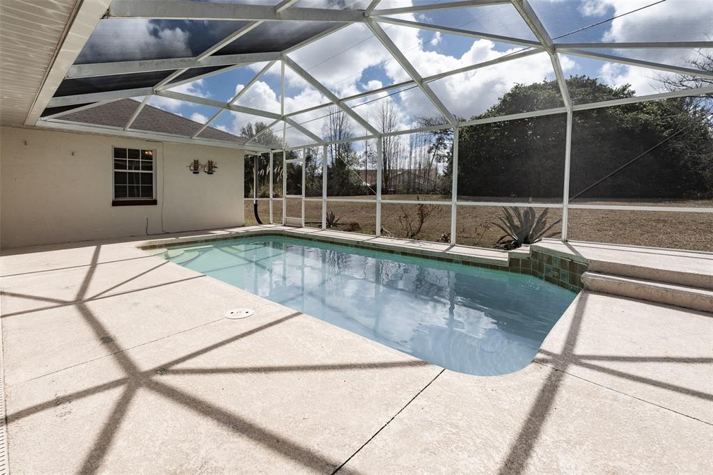 A rectangular swimming pool sits on a concrete patio enclosed by a white screen cage — 3948 SW 157TH PLACE ROAD, OCALA, FL