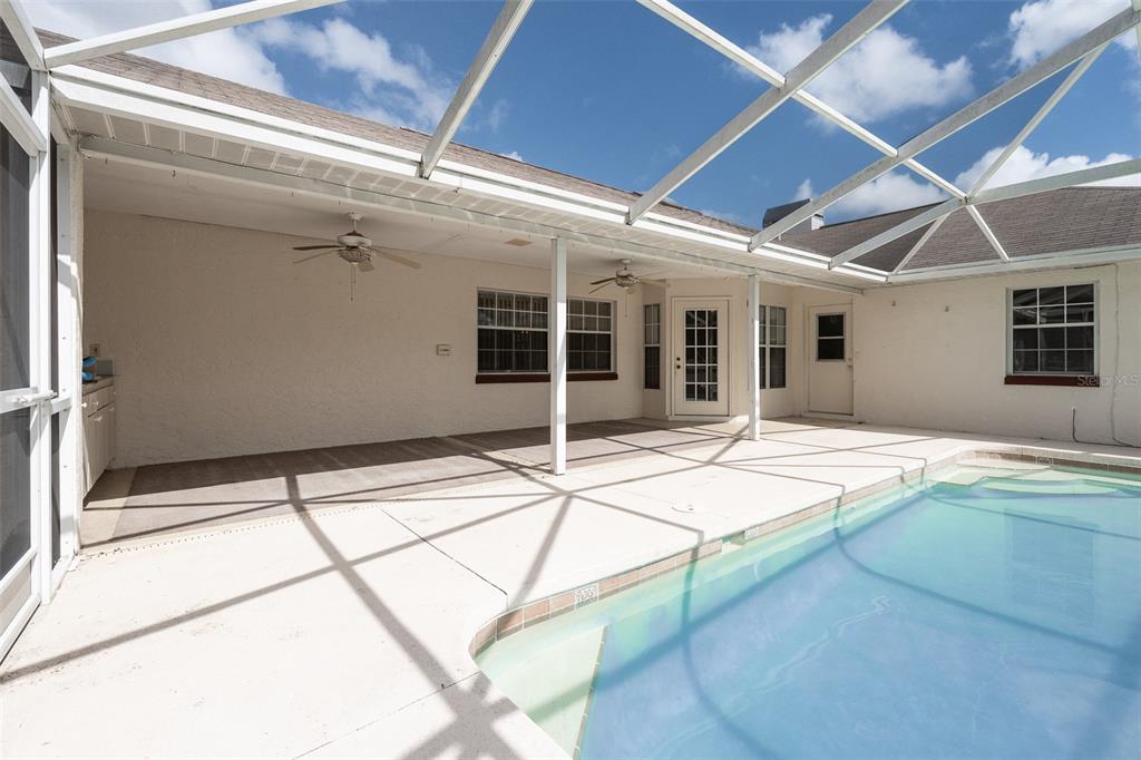 A screened-in patio features a swimming pool, ceiling fans, and light-colored exterior walls — 3948 SW 157TH PLACE ROAD, OCALA, FL