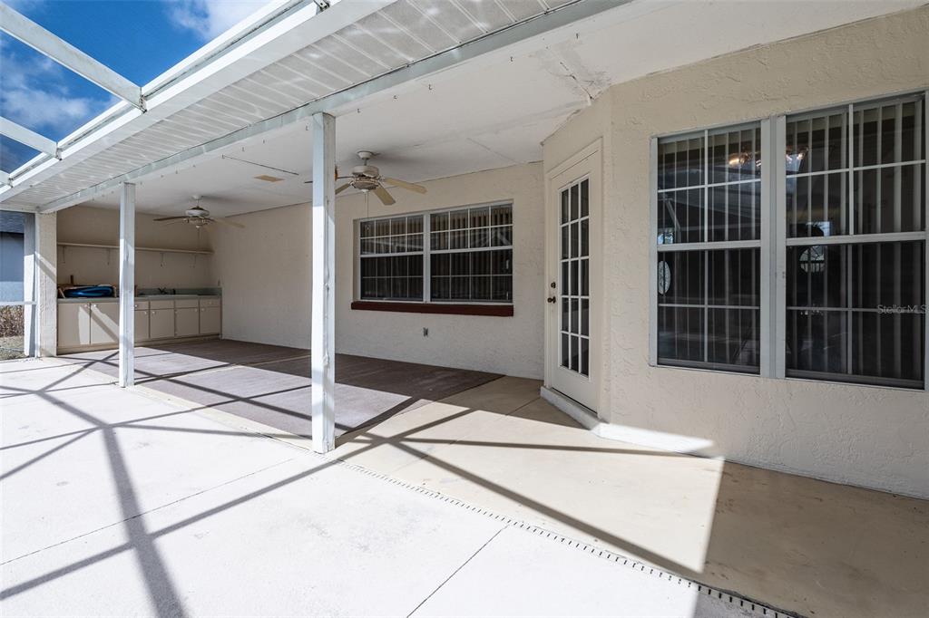 A covered patio features a concrete floor, ceiling fans, and a built-in outdoor kitchen area — 3948 SW 157TH PLACE ROAD, OCALA, FL