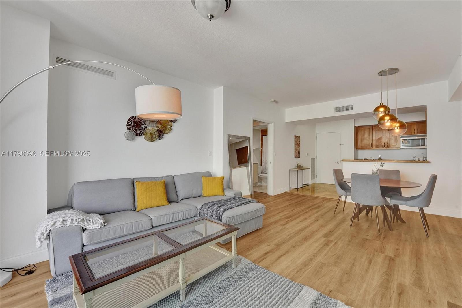 A living room and dining area feature light wood flooring, a gray sectional, and pendant lighting — 1745 E Hallandale Beach Blvd # 2105W, Hallandale Beach FL 33009, HALLANDALE BEACH, FL