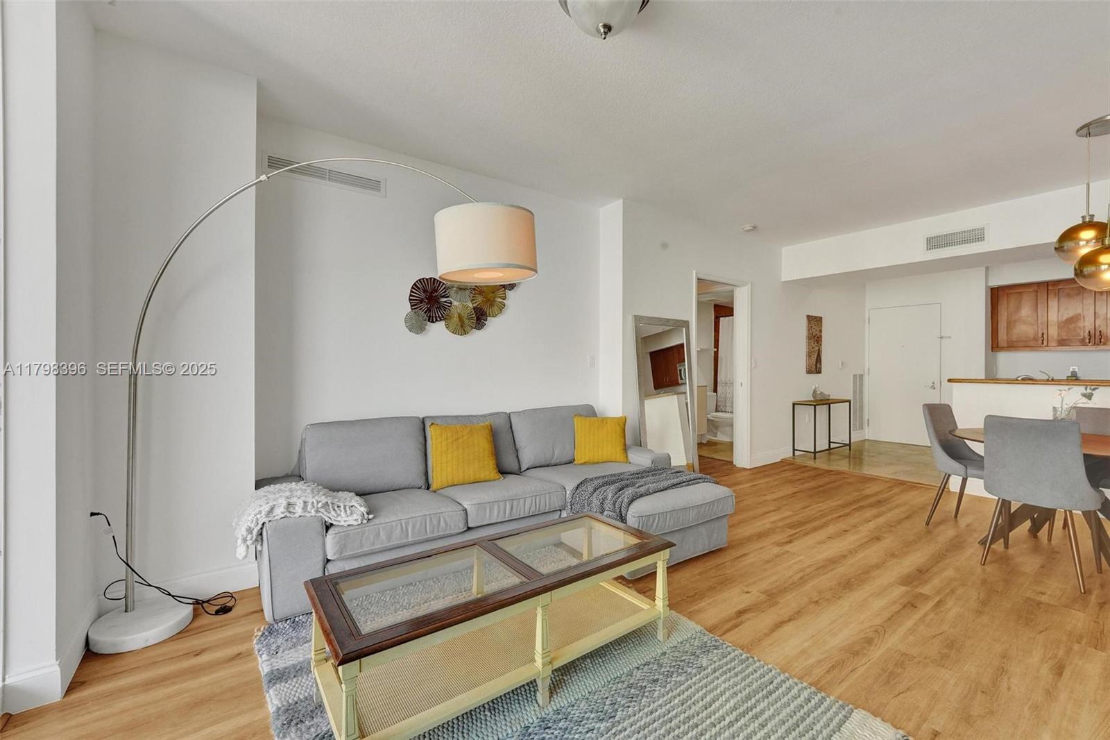A living room features a gray sectional sofa, a glass-top coffee table, and wood flooring — 1745 E Hallandale Beach Blvd # 2105W, Hallandale Beach FL 33009, HALLANDALE BEACH, FL