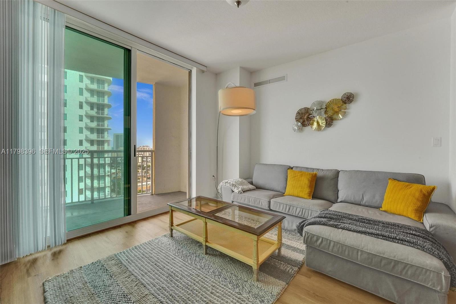 A living room features a gray sectional sofa, a glass-topped coffee table, and a balcony — 1745 E Hallandale Beach Blvd # 2105W, Hallandale Beach FL 33009, HALLANDALE BEACH, FL