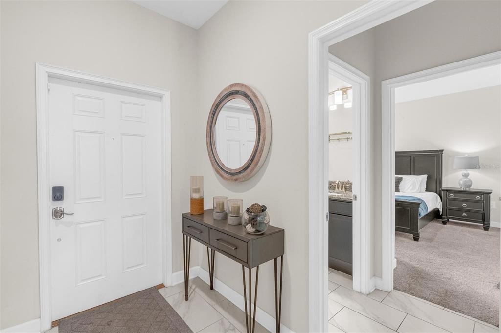 An entryway features a white door, a console table with decor, and a bedroom view — 3080 JULIET DRIVE, KISSIMMEE, FL