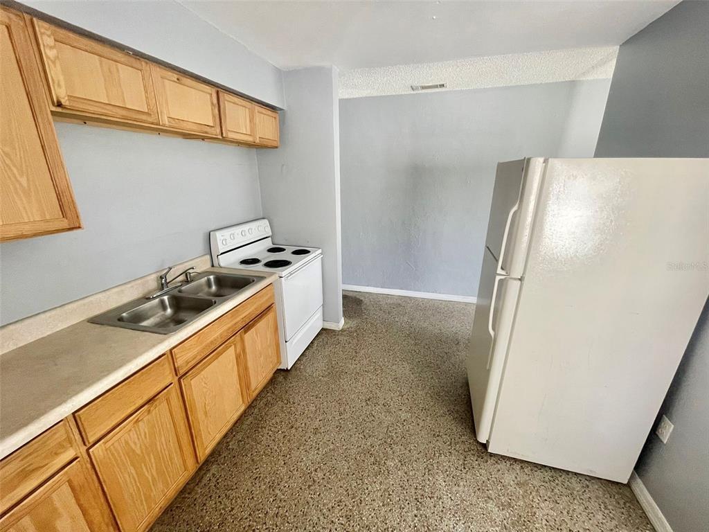 A kitchen features light wood cabinets, a double sink, a white stove, and a refrigerator — 4615 EDGEWATER DRIVE, ORLANDO, FL