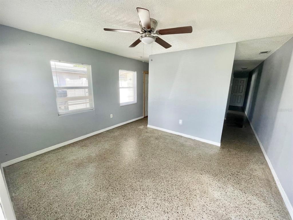 A room with light gray walls, a ceiling fan, and speckled concrete flooring — 4615 EDGEWATER DRIVE, ORLANDO, FL