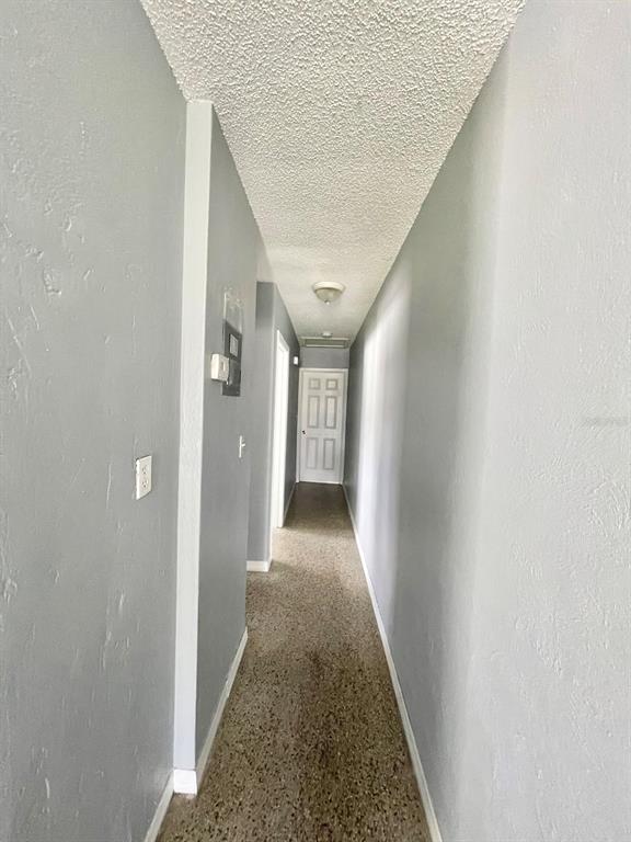 A long, narrow hallway with gray walls, a textured ceiling, and speckled flooring — 4615 EDGEWATER DRIVE, ORLANDO, FL