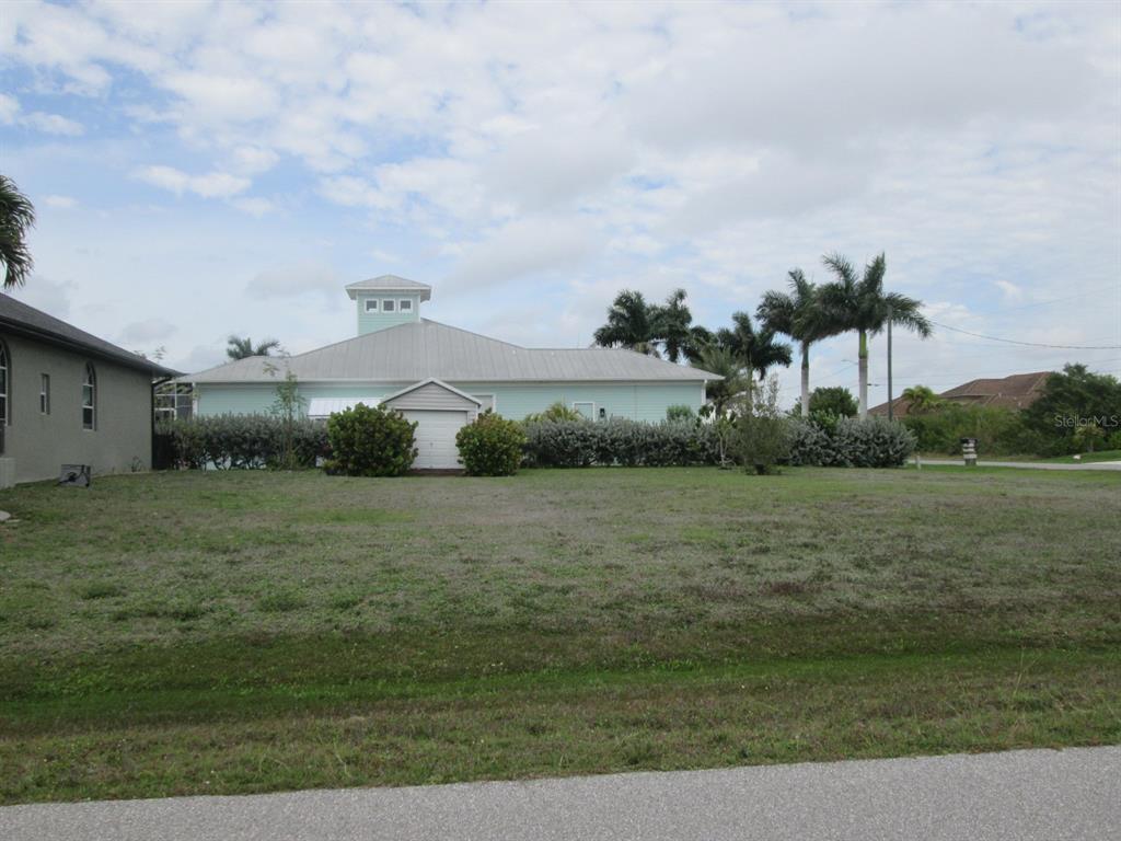 A vacant, grassy lot sits in front of a light green house with a cupola — 15352 POTTSTOWN AVENUE, PORT CHARLOTTE, FL