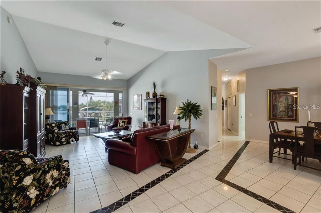 A spacious living and dining area with tiled floors, vaulted ceilings, and a water view — 15352 POTTSTOWN AVENUE, PORT CHARLOTTE, FL