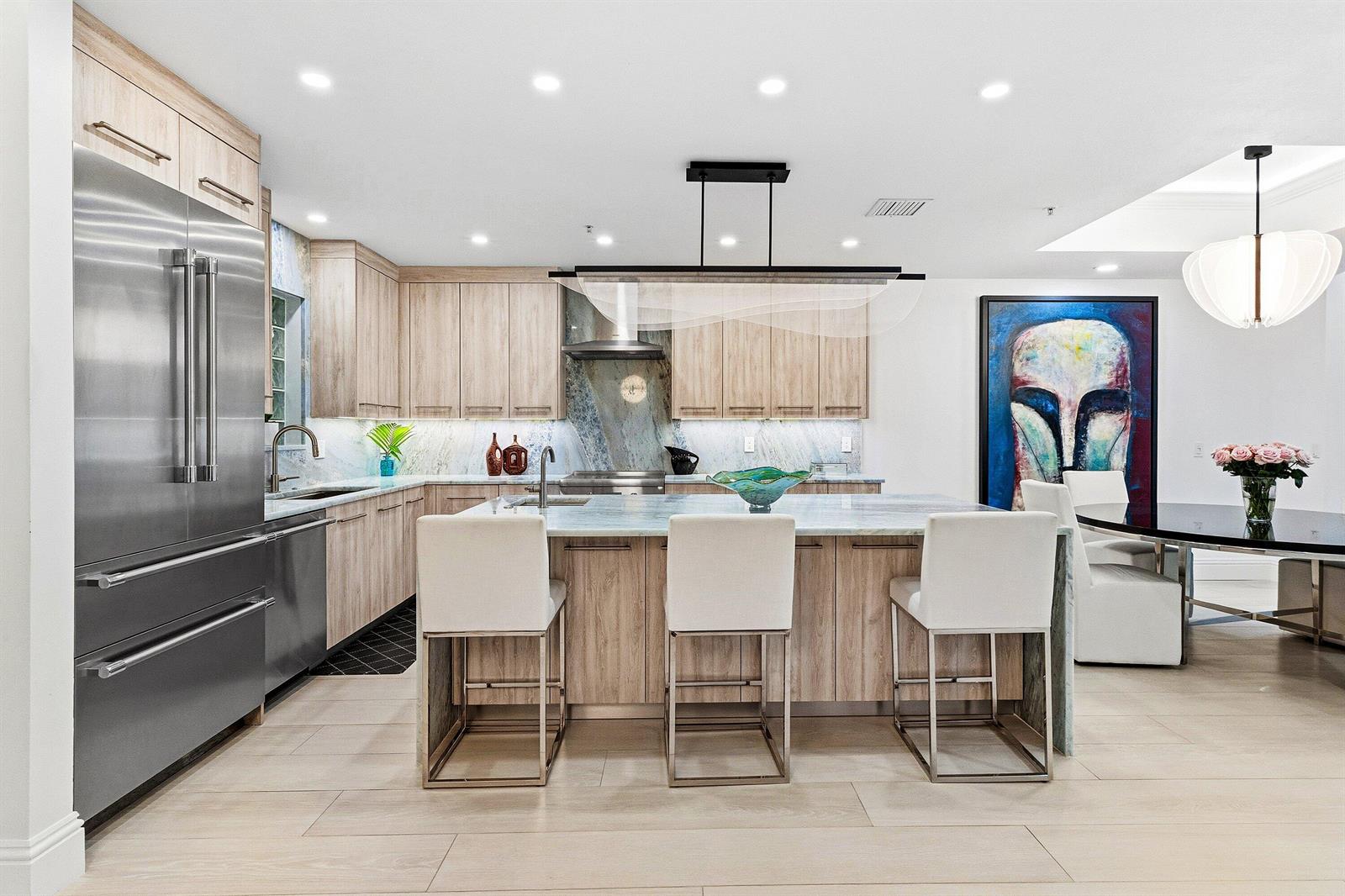 A modern kitchen features light wood cabinets, a marble island, and stainless steel appliances — 122 SE 6th Avenue # 3, Delray Beach FL 33483, DELRAY BEACH, FL