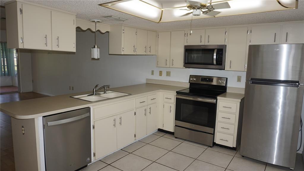 A kitchen with off-white cabinets, stainless steel appliances, a double sink, and tiled flooring — 12543 DEARBORN DRIVE, HUDSON, FL