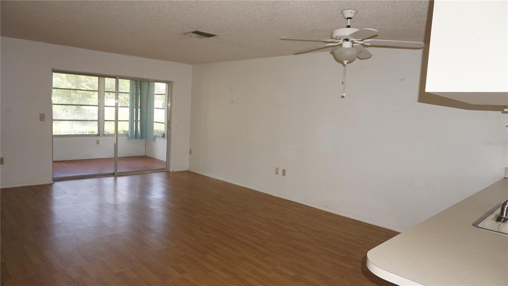 A living room with wood-look flooring, a ceiling fan, and sliding glass doors to a porch — 12543 DEARBORN DRIVE, HUDSON, FL