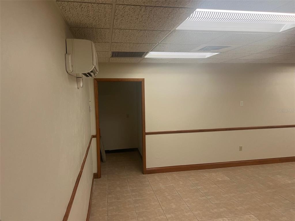 An interior room features beige walls with chair rail molding, tiled floors, and a drop ceiling — 3501 SW 2ND AVENUE UNIT 2300, GAINESVILLE, FL