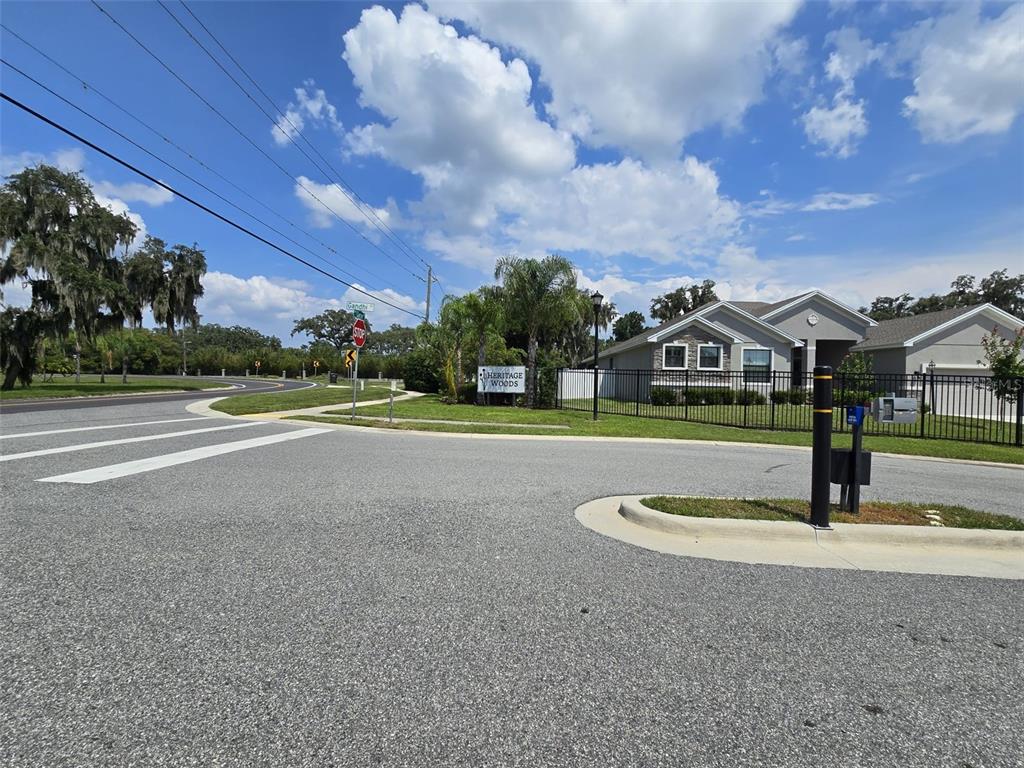 A street-level view shows the entrance sign for Heritage Woods next to a residential house — 605 ARIA DR., LAKELAND, FL
