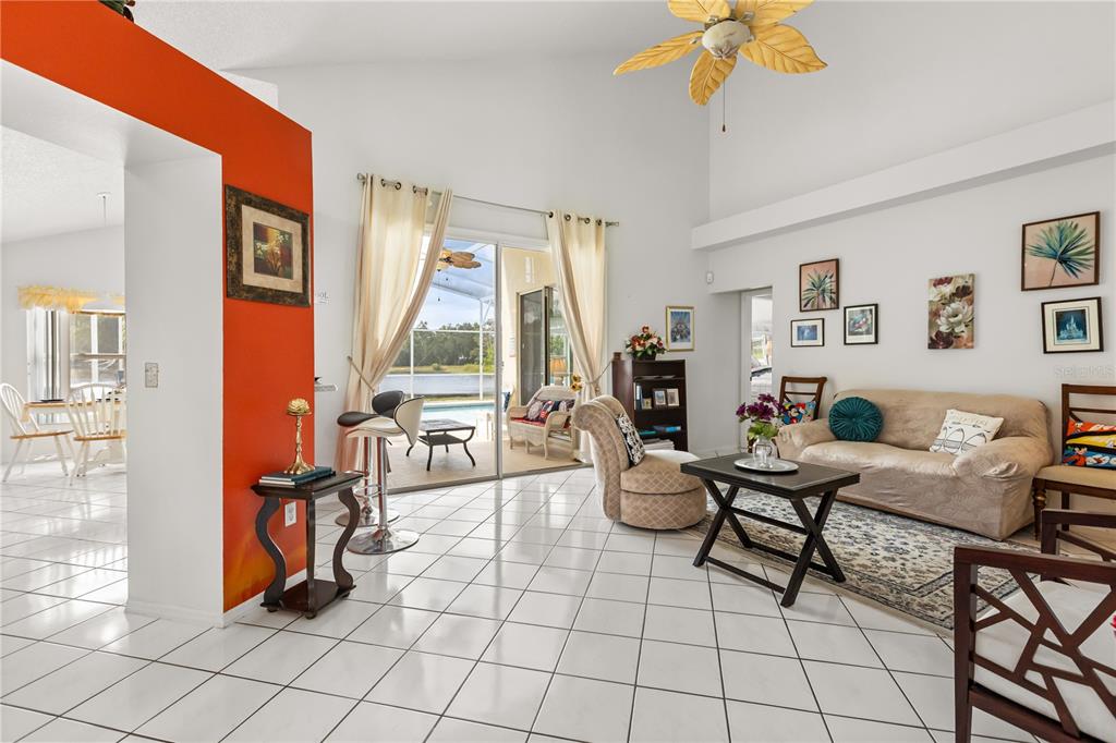 A living room with white tile floors, a vaulted ceiling, and a view of a pool — 2703 CHATHAM, KISSIMMEE, FL