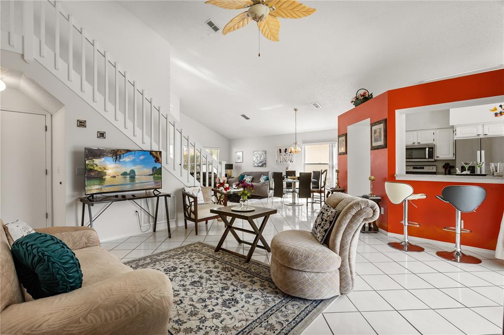 A living room with tile floors, a staircase, and an open kitchen with a breakfast bar — 2703 CHATHAM, KISSIMMEE, FL