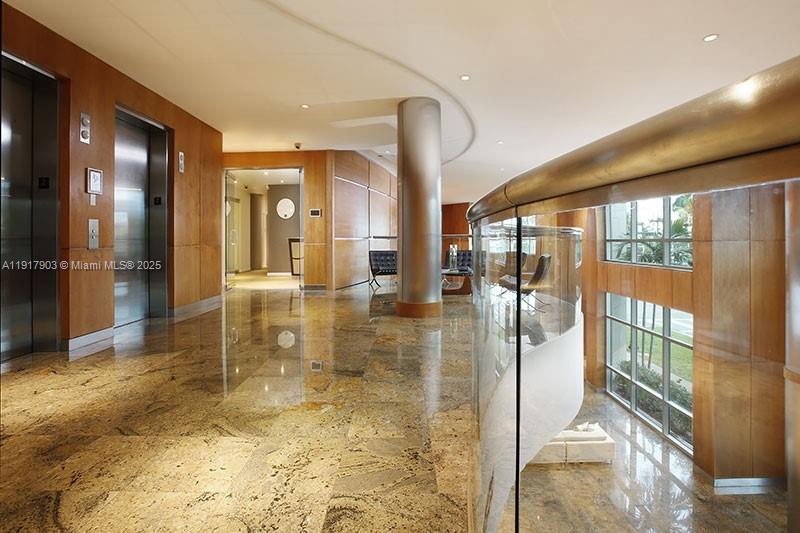 A modern lobby features polished granite floors, wood-paneled walls, elevators, and a curved glass railing — 1000 5th St # 103, Miami Beach FL 33139, MIAMI BEACH, FL