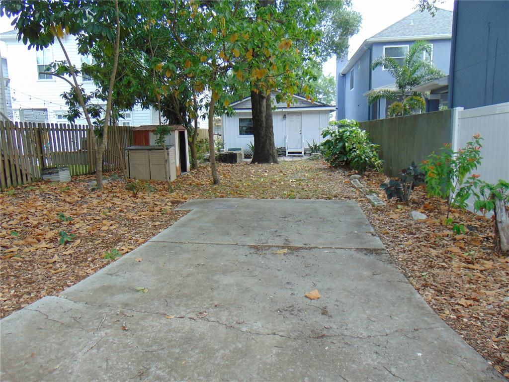 A concrete patio sits in a backyard with a small shed and a detached garage — 406 S ORLEANS AVENUE, TAMPA, FL