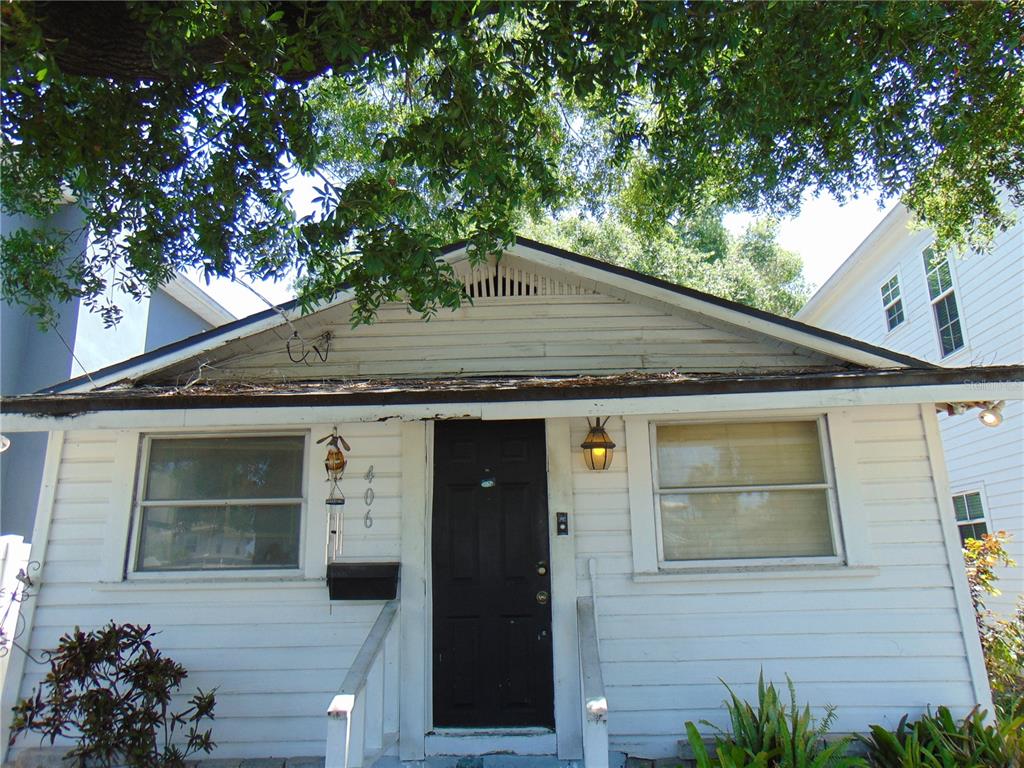 The exterior of a small, white, single-story house with a black front door and siding — 406 S ORLEANS AVENUE, TAMPA, FL
