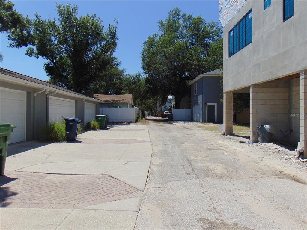 An alleyway view showing garage doors on the left and a building under construction — 406 S ORLEANS AVENUE, TAMPA, FL