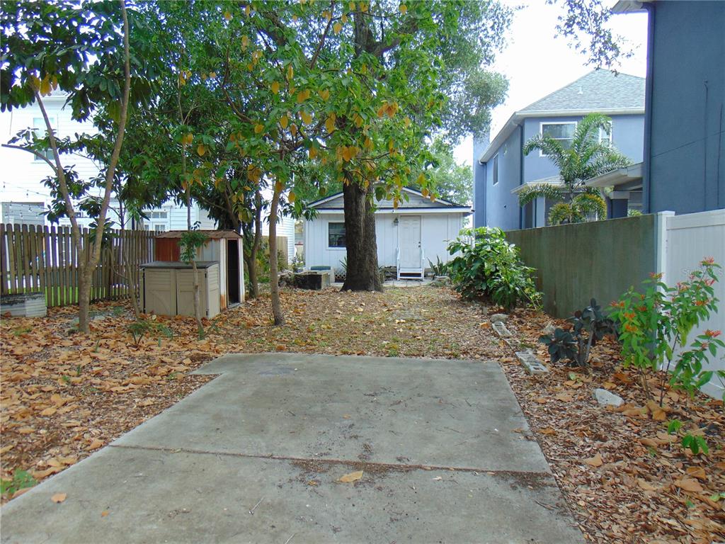 A backyard features a concrete patio, a small shed, a detached building, and mature trees — 406 S ORLEANS AVENUE, TAMPA, FL
