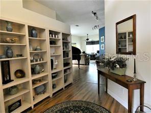 A hallway features built-in white bookshelves, wood-look flooring, and a console table with a mirror — 4062 WESTBOURNE CIRCLE, SARASOTA, FL