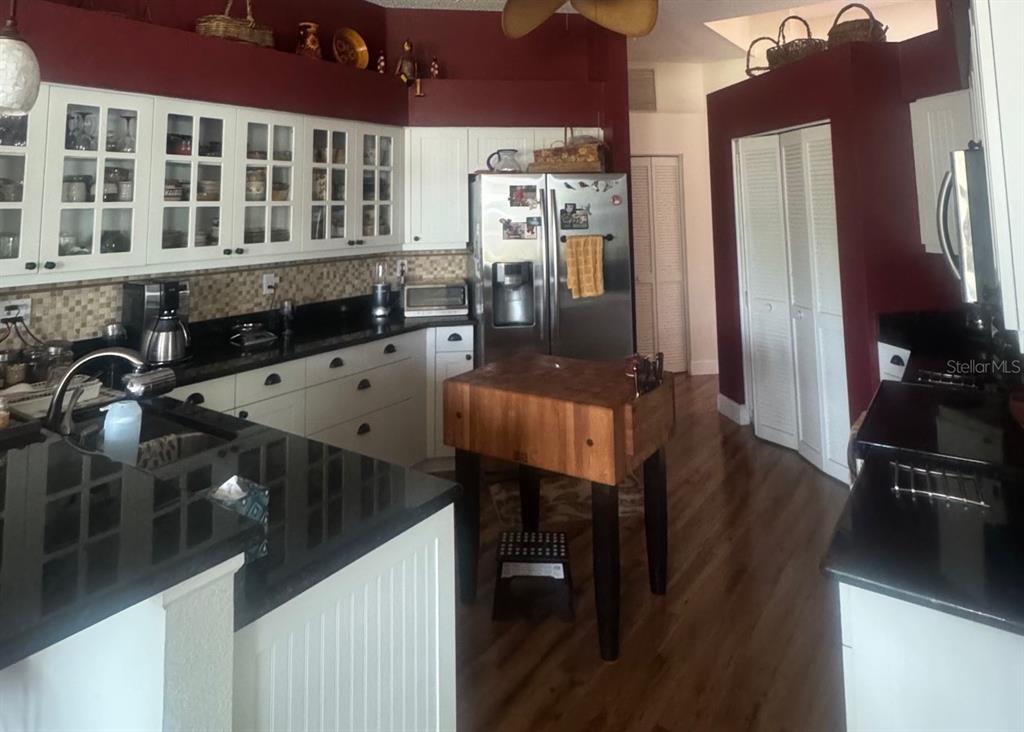 A kitchen features white cabinets, black countertops, a wooden butcher block island, and red walls — 4062 WESTBOURNE CIRCLE, SARASOTA, FL