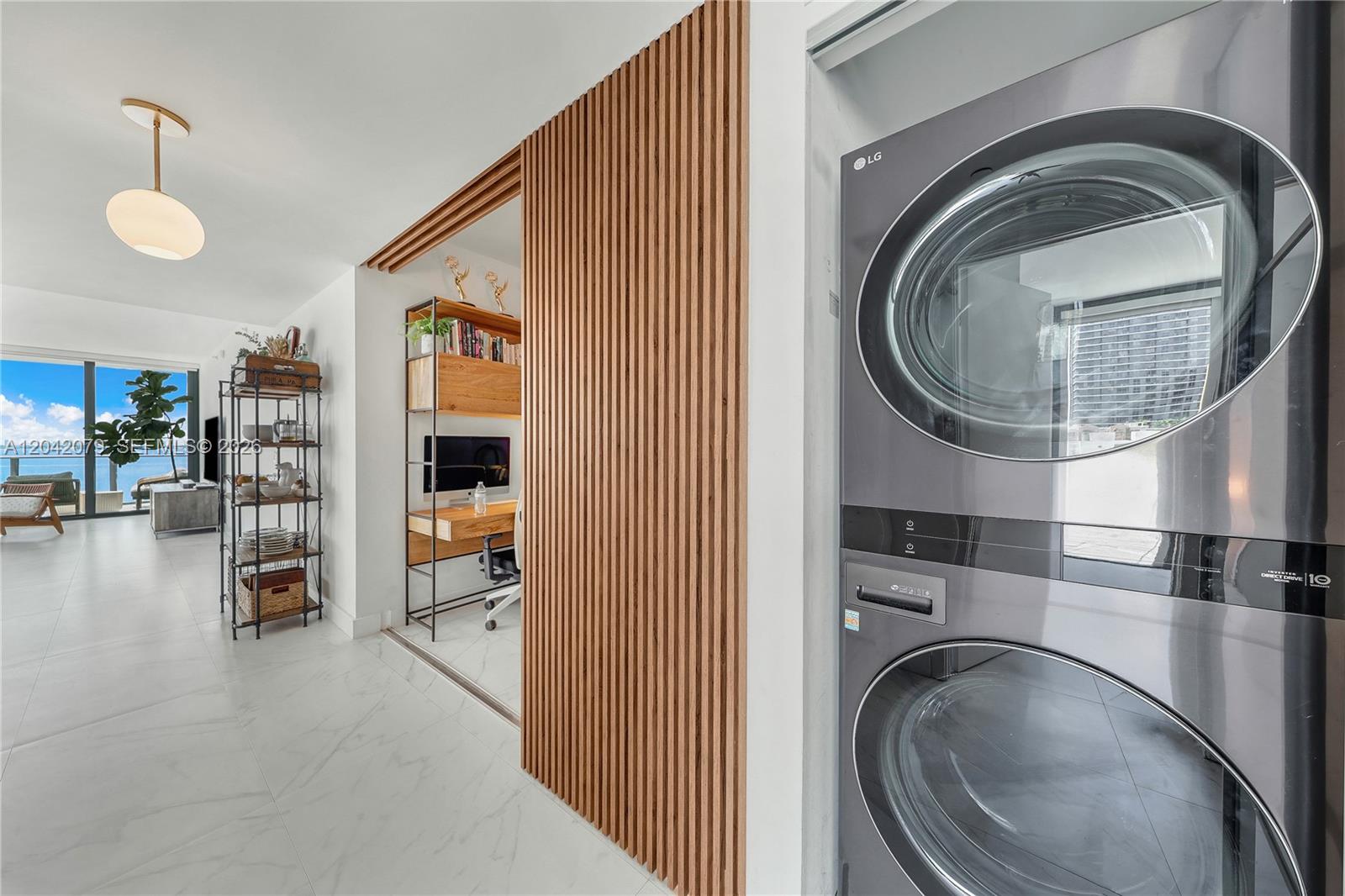 A laundry closet with a stacked washer-dryer sits beside a room with wood-slat wall paneling — 460 NE 28th St # 701, Miami FL 33137, MIAMI, FL