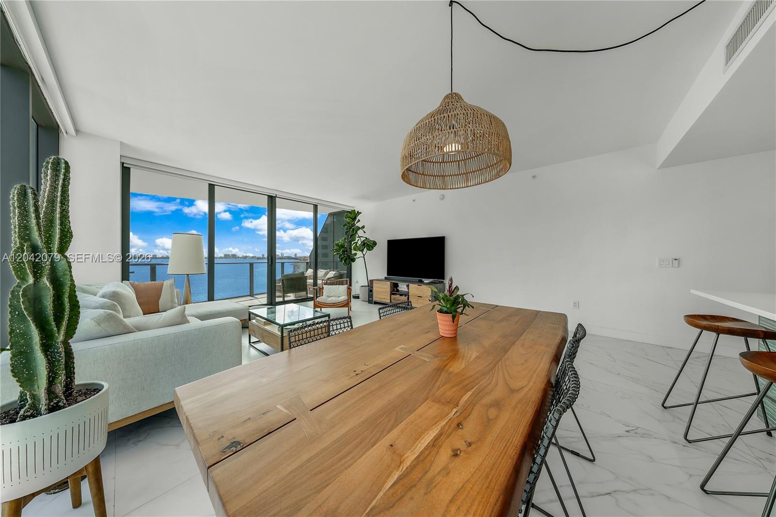 A modern living and dining area features a wooden table, white floors, and balcony views — 460 NE 28th St # 701, Miami FL 33137, MIAMI, FL