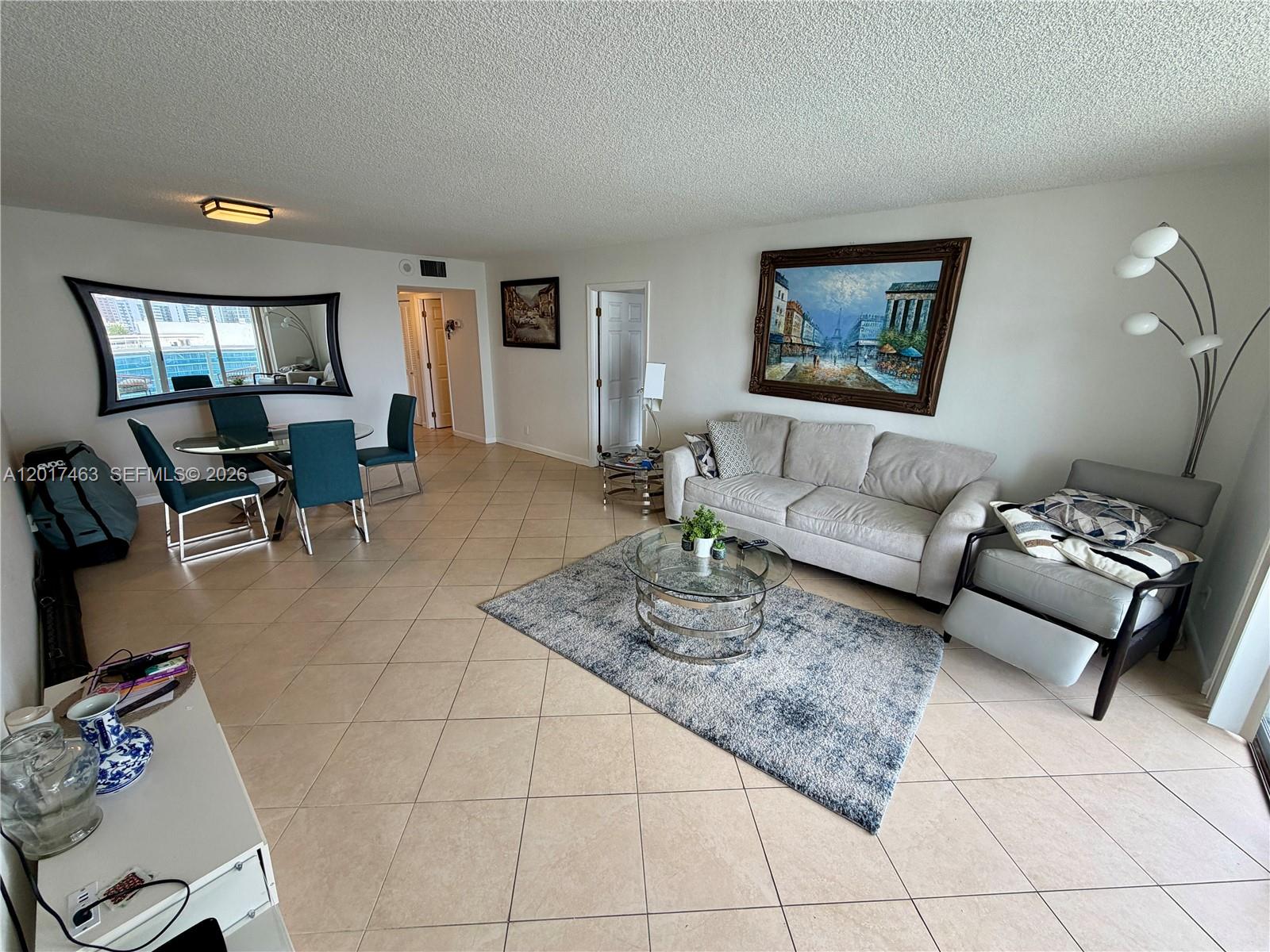 A living and dining area features tile floors, a neutral sofa, and a glass-topped table — 3800 S Ocean Dr # 1208, Hollywood FL 33019, HOLLYWOOD, FL