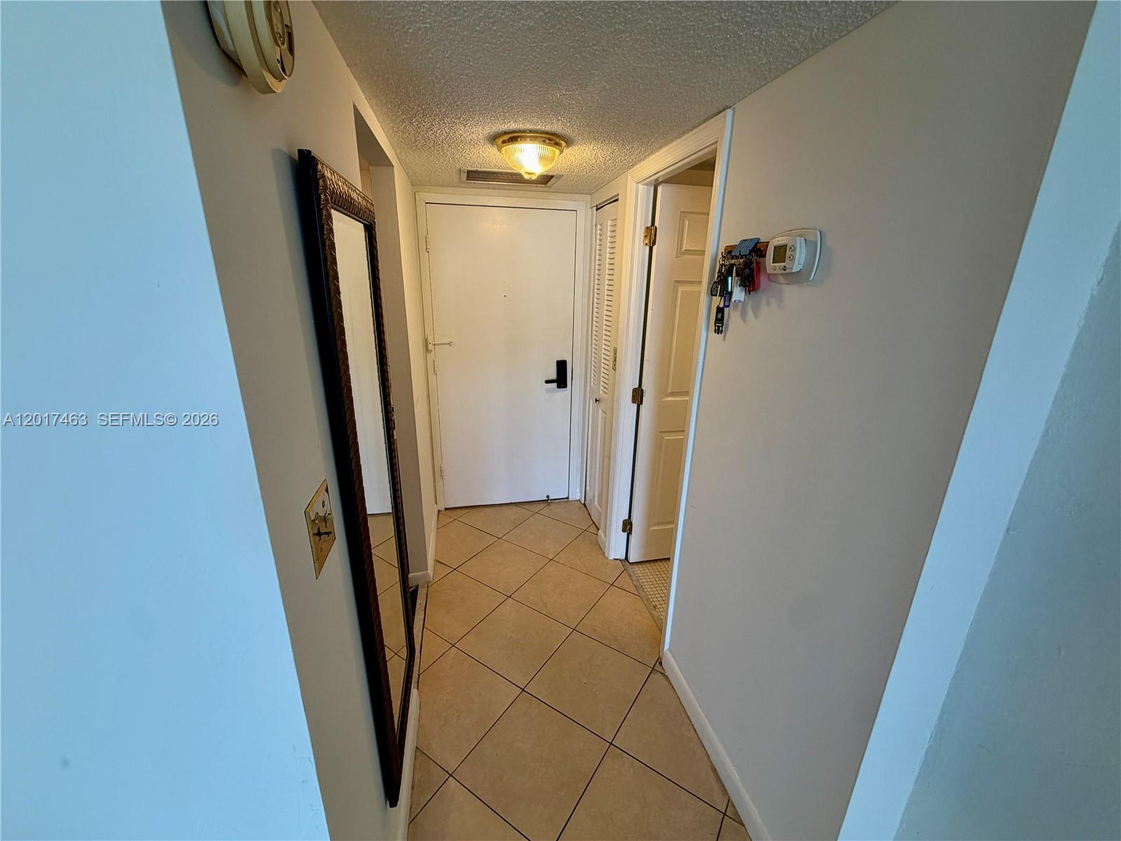 A tiled entryway features a full-length mirror, a white door, and a wall-mounted thermostat — 3800 S Ocean Dr # 1208, Hollywood FL 33019, HOLLYWOOD, FL