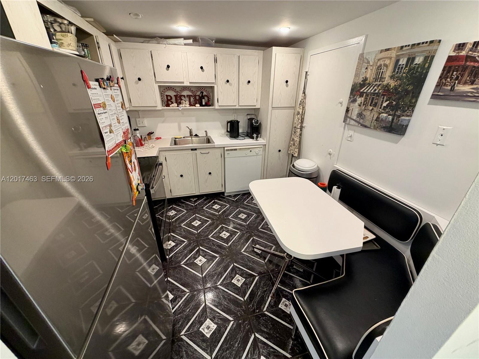 A small kitchen features white cabinets, stainless steel appliances, and black and white patterned flooring — 3800 S Ocean Dr # 1208, Hollywood FL 33019, HOLLYWOOD, FL