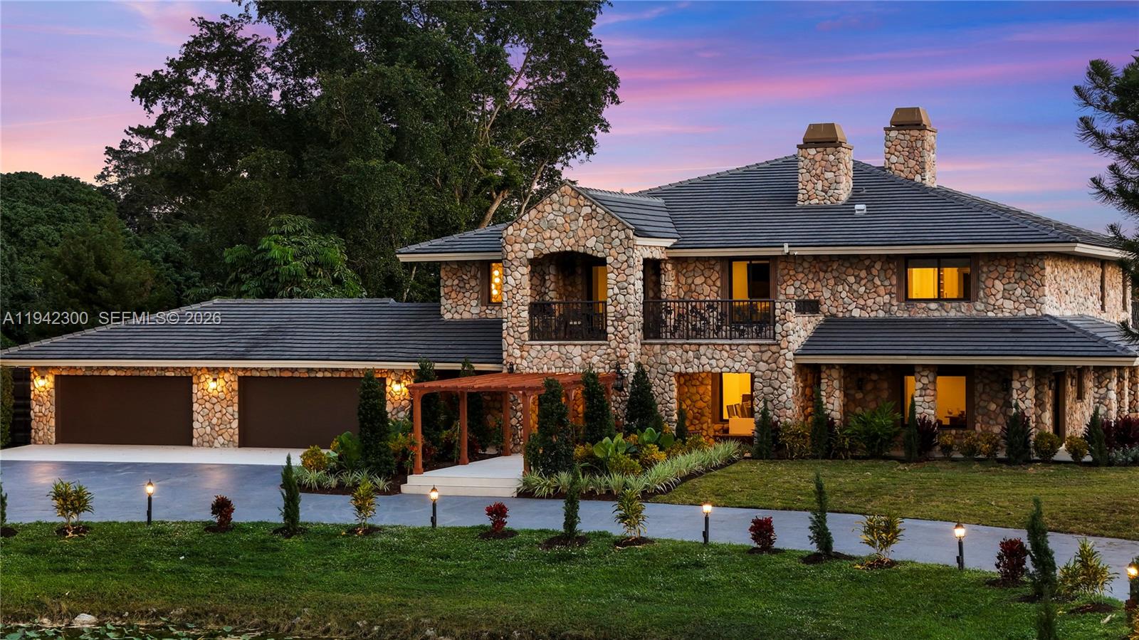 A two-story stone house features a dark tiled roof, a balcony, and a three-car garage — 3320 SW 121st Ave, Davie FL 33330, DAVIE, FL