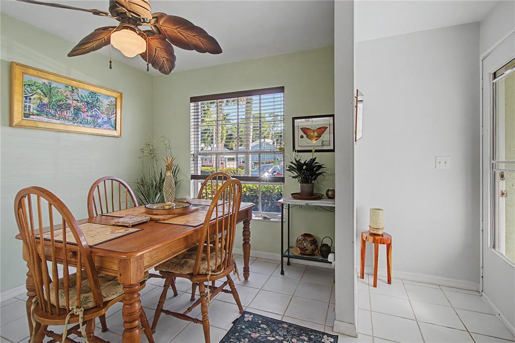 A dining room with a wooden table, spindle chairs, tile flooring, and a palm-leaf ceiling fan — 28201 PINE HAVEN WAY UNIT 145, BONITA SPRINGS, FL