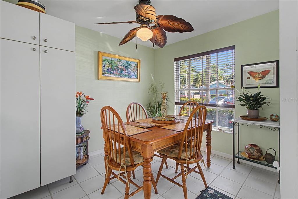 A dining room features a wooden table, spindle chairs, a ceiling fan, and light green walls — 28201 PINE HAVEN WAY UNIT 145, BONITA SPRINGS, FL