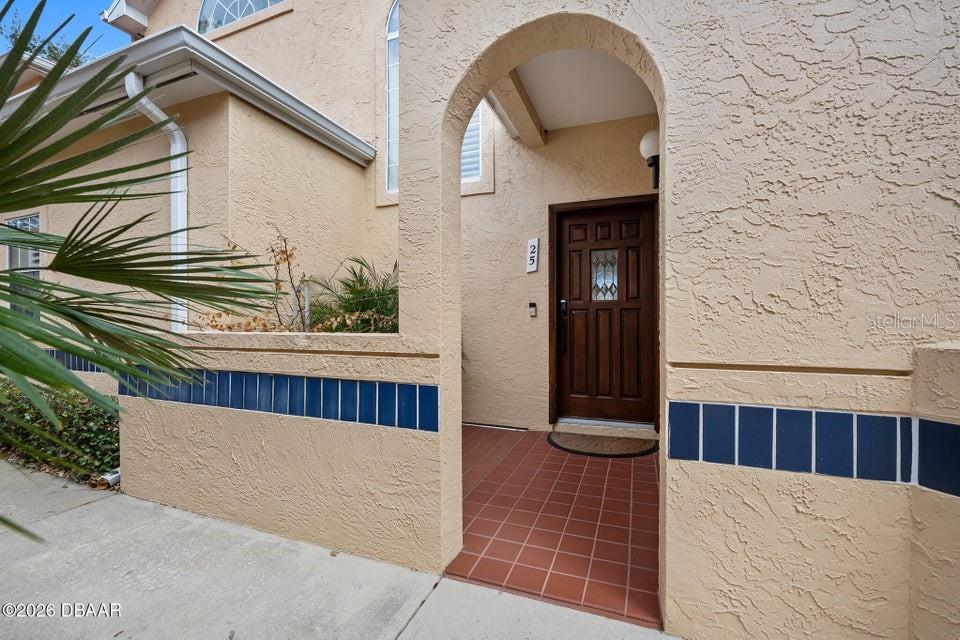 The exterior entrance features a stucco wall, a tiled walkway, and a wooden front door — 25 MARINA POINT PLACE, PALM COAST, FL