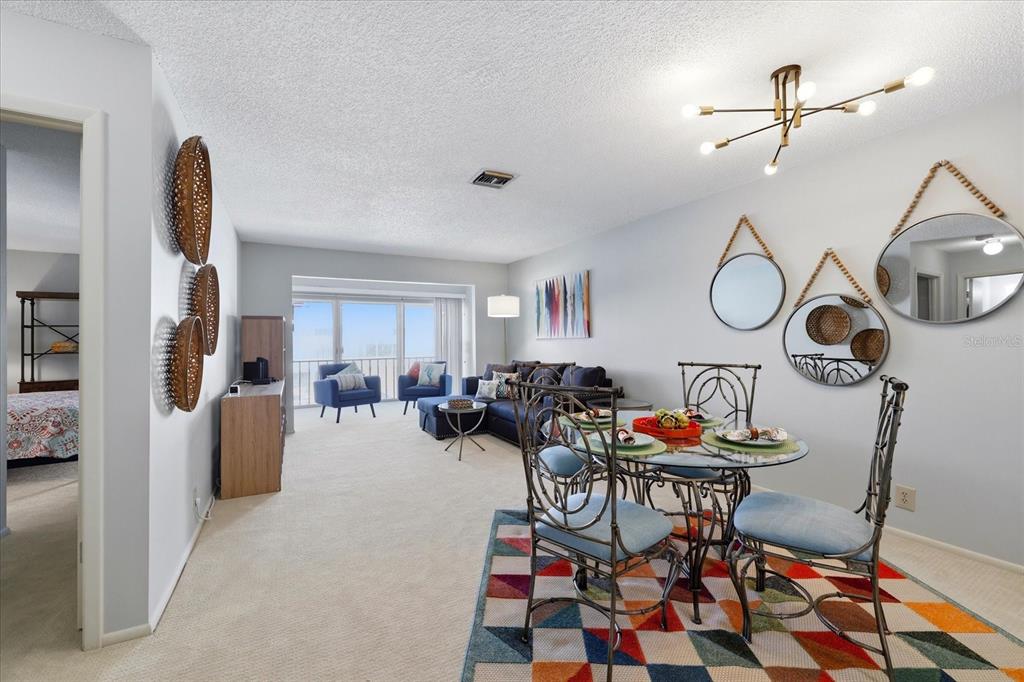 A dining area with a glass table and a living room with balcony access — 2060 MARILYN STREET UNIT 211, CLEARWATER, FL