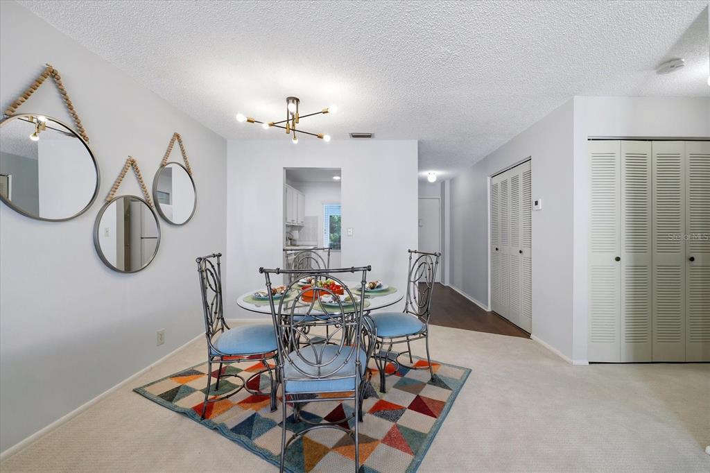 A dining area features a glass table, four chairs, a geometric rug, and wall mirrors — 2060 MARILYN STREET UNIT 211, CLEARWATER, FL