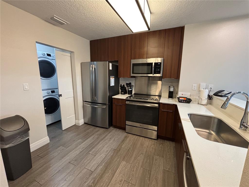 A kitchen features dark wood cabinets, stainless steel appliances, white countertops, and wood-look tile flooring — 14501 GROVE RESORT AVENUE UNIT 2530, WINTER GARDEN, FL