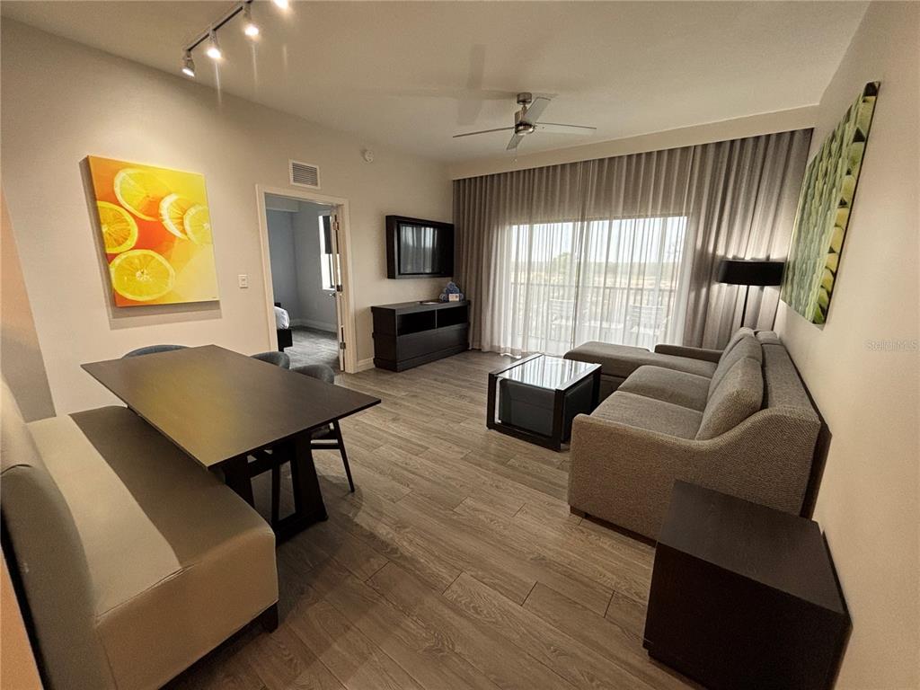 A living and dining area features wood-look flooring, a sectional sofa, and a dining table — 14501 GROVE RESORT AVENUE UNIT 2530, WINTER GARDEN, FL