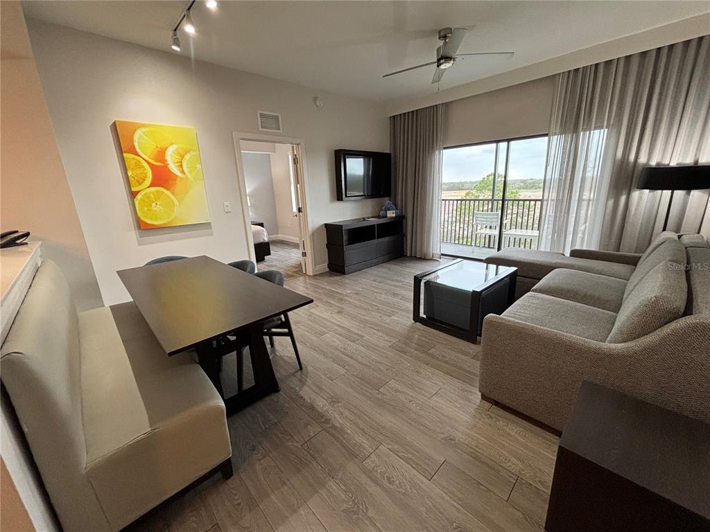 A living and dining area features wood-look flooring, a sofa, a dining table, and balcony access — 14501 GROVE RESORT AVENUE UNIT 2530, WINTER GARDEN, FL