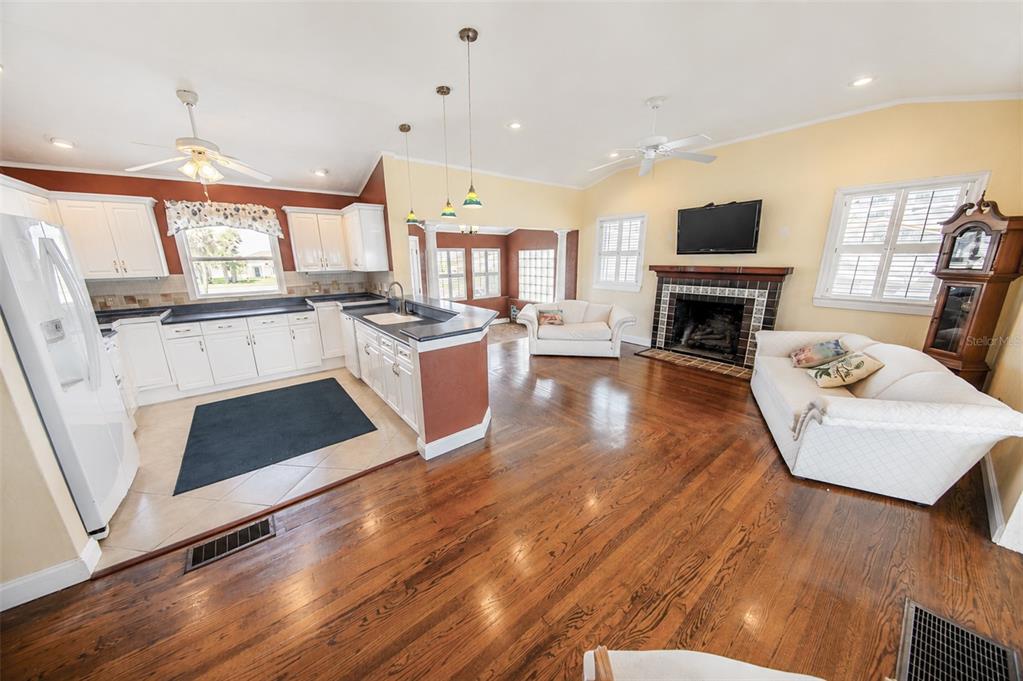 A living room with hardwood floors, a kitchen island, and a sofa facing the entrance — 3873 S ATLANTIC AVENUE, DAYTONA BEACH SHORES, FL