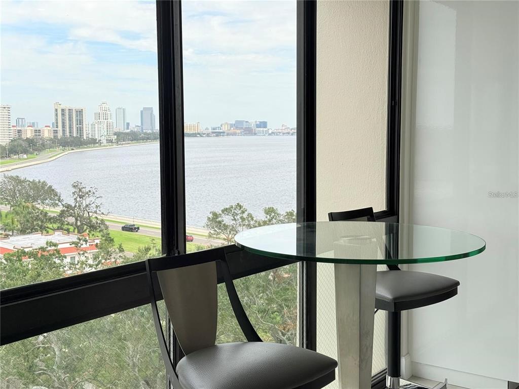 A glass-topped table and two chairs sit in front of a large window overlooking water — 3301 BAYSHORE BOULEVARD UNIT 1001E, TAMPA, FL
