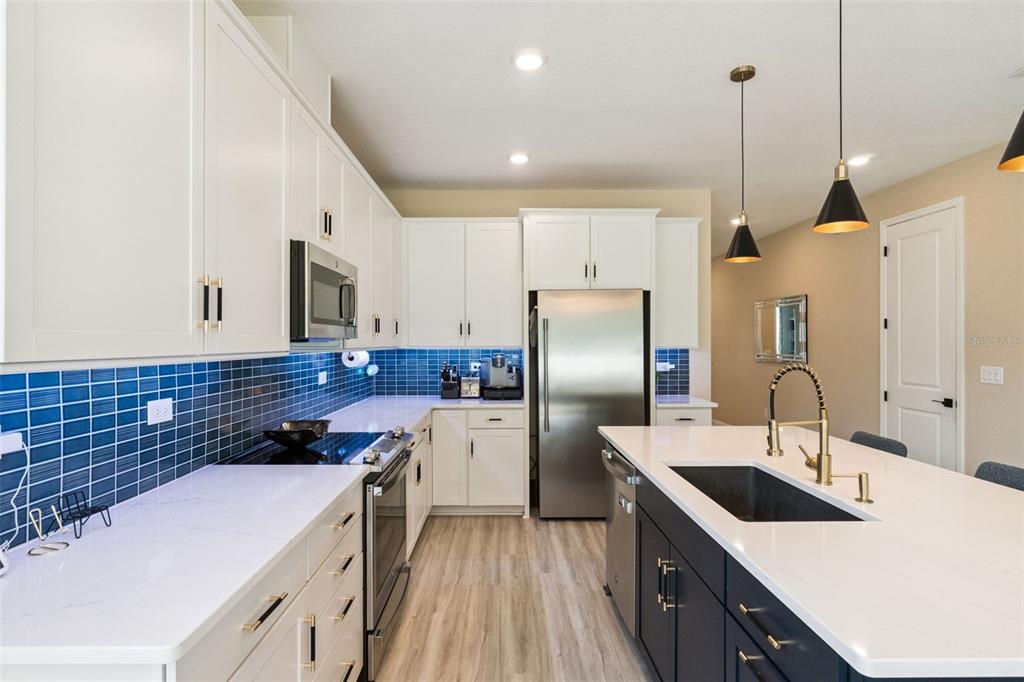 A modern kitchen features white upper cabinets, a dark blue island, and a blue backsplash — 4148 SOUTHERN VISTA LOOP, ST CLOUD, FL