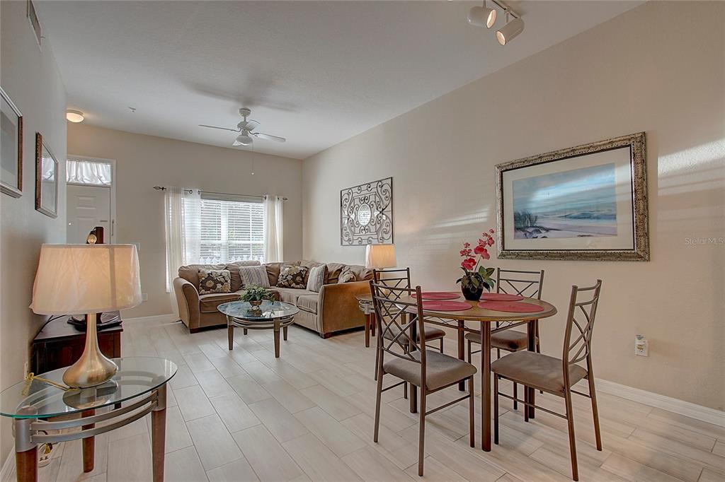 A living and dining area features light tile flooring, a beige sofa, and a dining set — 4003 SAN SABASTIAN DRIVE UNIT 106, KISSIMMEE, FL