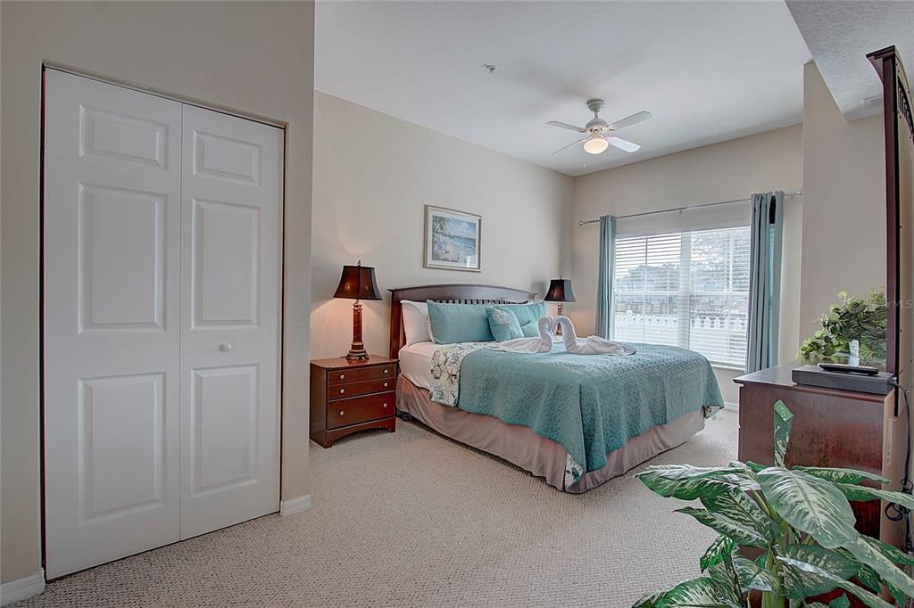 A bedroom features a queen bed with teal bedding, a ceiling fan, and a closet — 4003 SAN SABASTIAN DRIVE UNIT 106, KISSIMMEE, FL