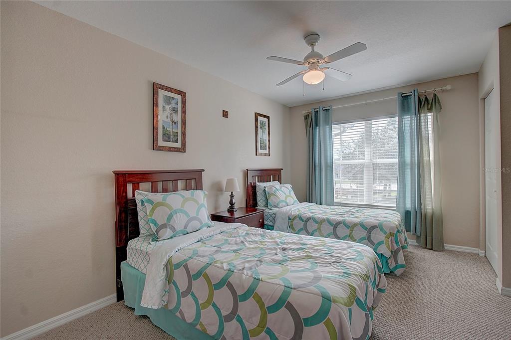 A bedroom features two twin beds with patterned bedding, a ceiling fan, and window curtains — 4003 SAN SABASTIAN DRIVE UNIT 106, KISSIMMEE, FL