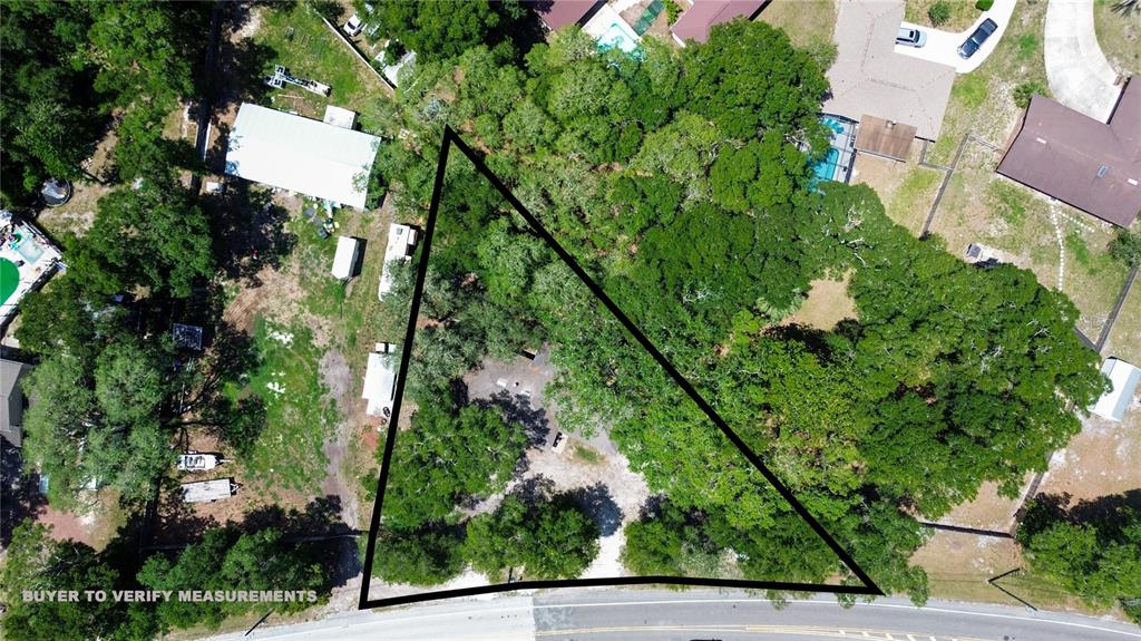 An aerial view shows a triangular lot with mature trees bordering a paved road — 745 WILDWOOD DRIVE, ST AUGUSTINE, FL