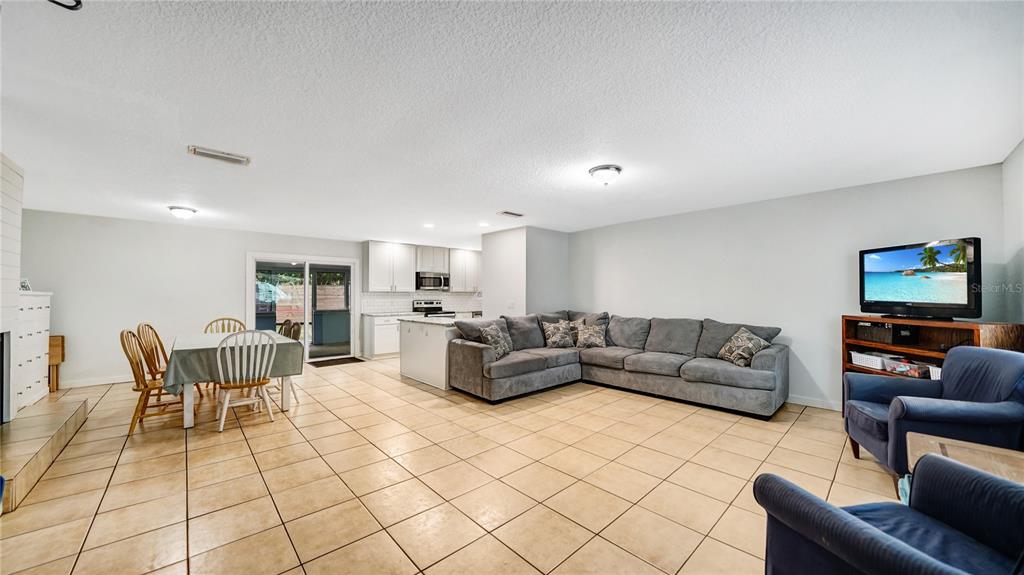 An open-concept living and dining area features tile flooring, a gray sectional, and a kitchen — 745 WILDWOOD DRIVE, ST AUGUSTINE, FL